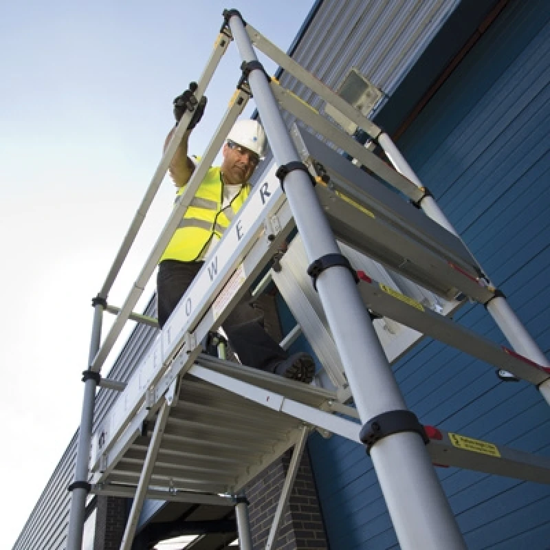 Worker using Zarges Teletower Aluminium Telescopic Scaffold Tower beside a building.