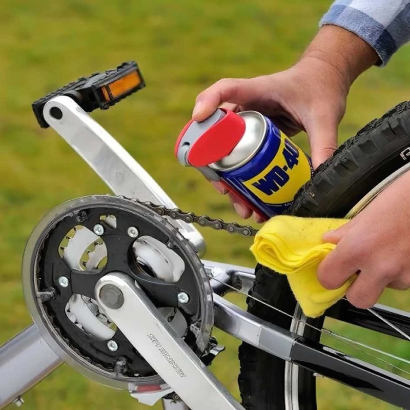 Person lubricating a bicycle chain with WD-40 and wiping it down with a cloth