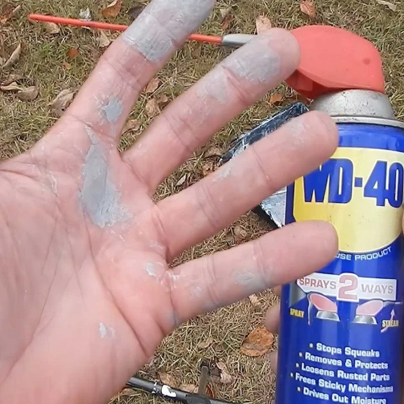 Hand holding WD-40 spray can after cleaning paint from skin