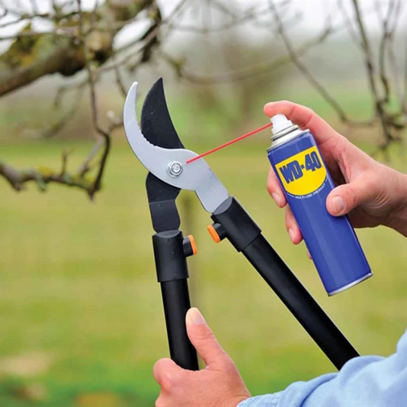 Person applying WD-40 to pruning shears to keep blades clean and rust-free