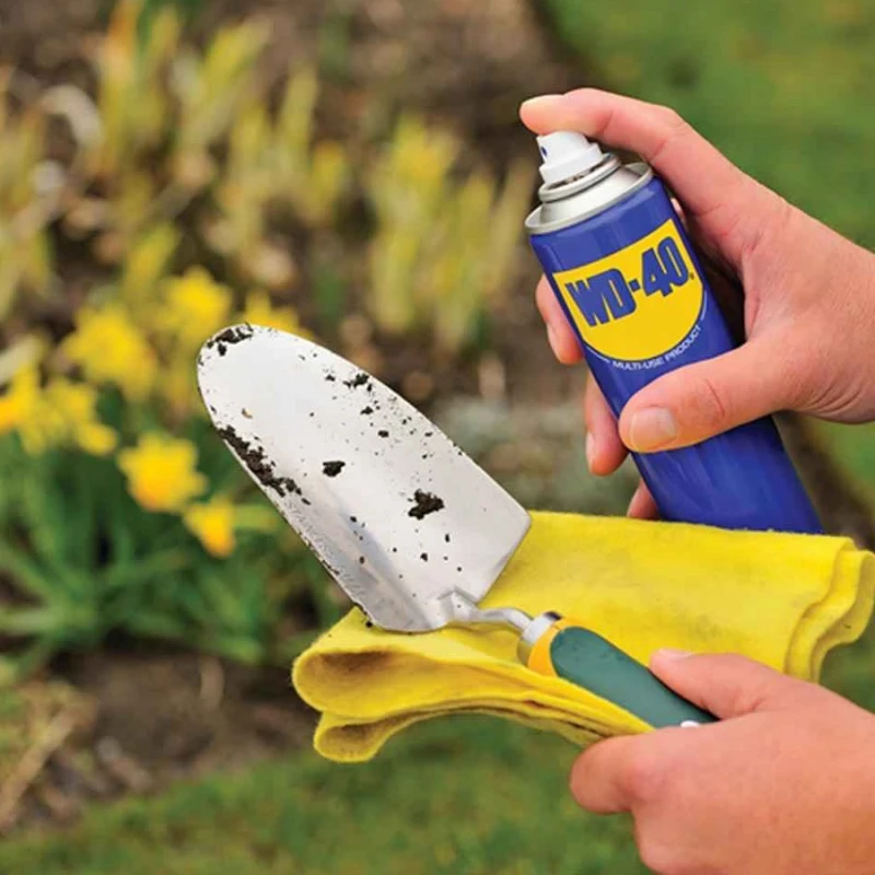 WD-40 spray applied to a garden trowel for removing dirt and preventing corrosion