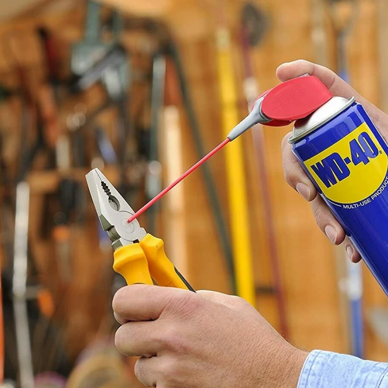 WD-40 being sprayed onto a pair of pliers in a workshop setting for tool maintenance