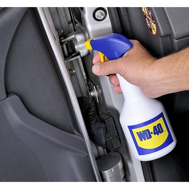 Hand applying WD-40 spray to a vehicle door hinge to reduce squeaks and prevent rust