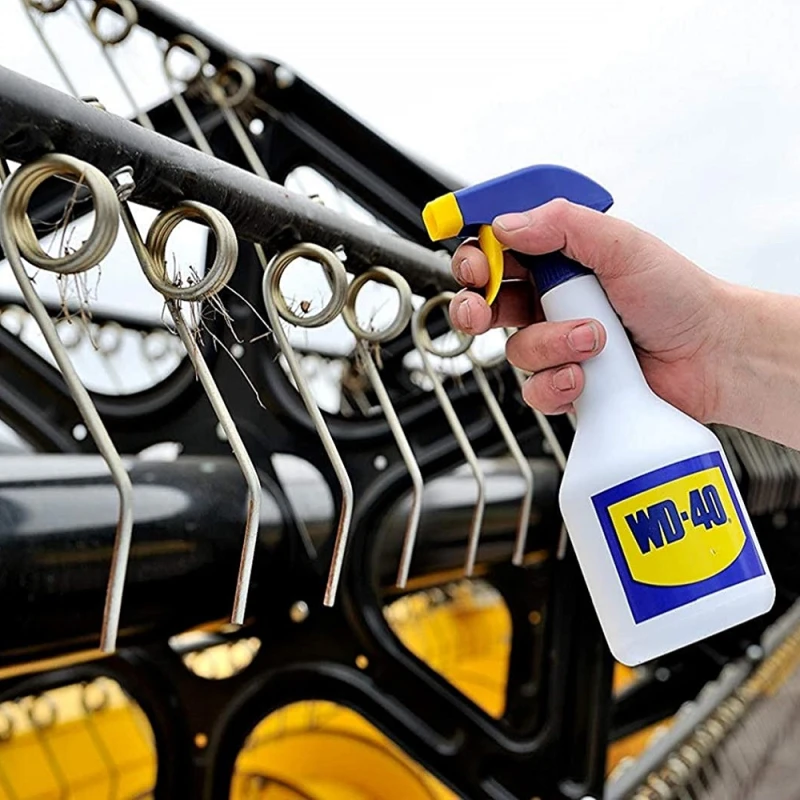 Hand using WD-40 spray on outdoor metal equipment to protect against rust and wear
