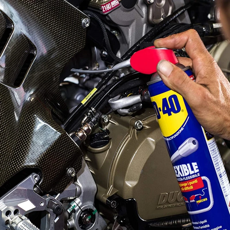 Person using WD40 Multi-Use Smart Flexible Straw Maintenance Aerosol on motorcycle engine.