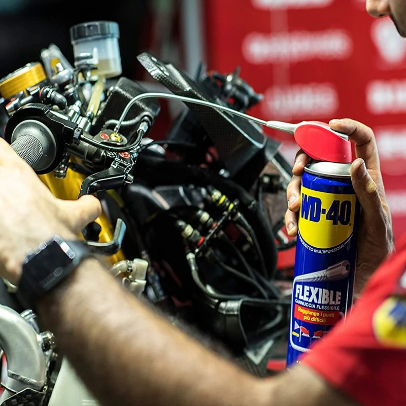 Person using WD40 Multi-Use Smart Flexible Straw Maintenance Aerosol on a motorcycle part.