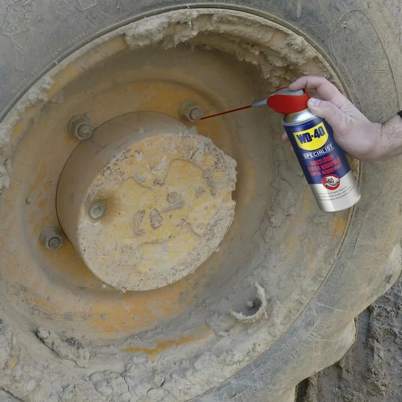 Hand applying WD40 Specialist Penetrant Fast Release Oil to a rusty wheel bolt.