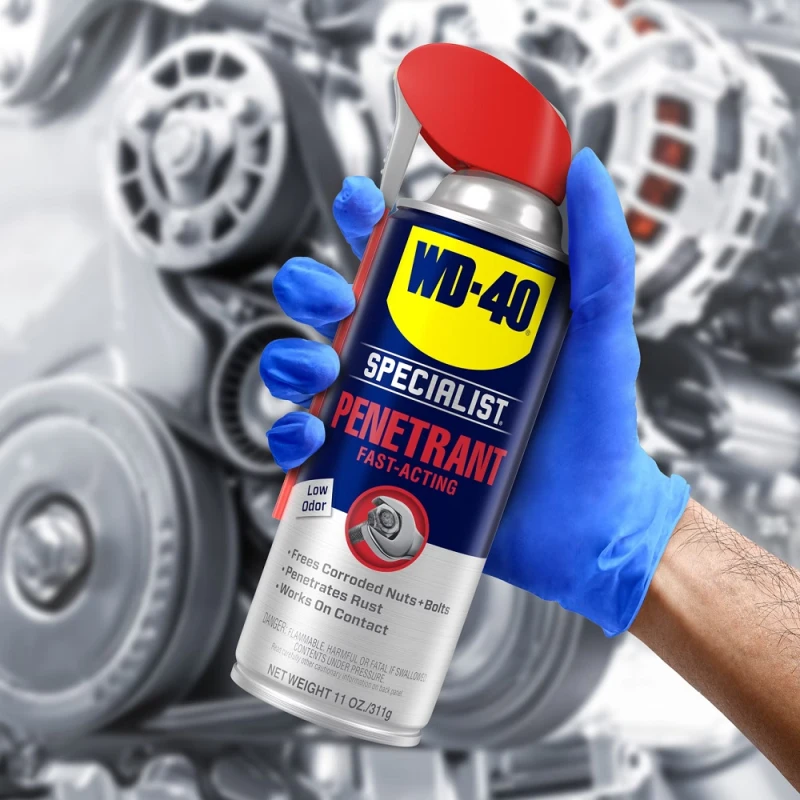 Person holding a can of WD40 Specialist Penetrant Fast Release Penetrating Oil in front of machinery.