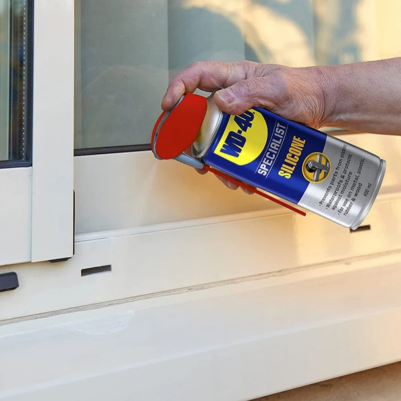Person applying WD40 Specialist High-Performance Silicone Spray to a window frame.