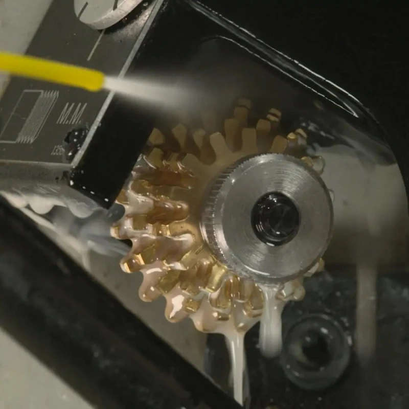 Close-up of a metal gear being sprayed with a degreaser.