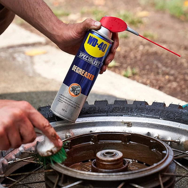 Person using WD40 Specialist Industrial Strength Degreaser Spray on a bicycle wheel.