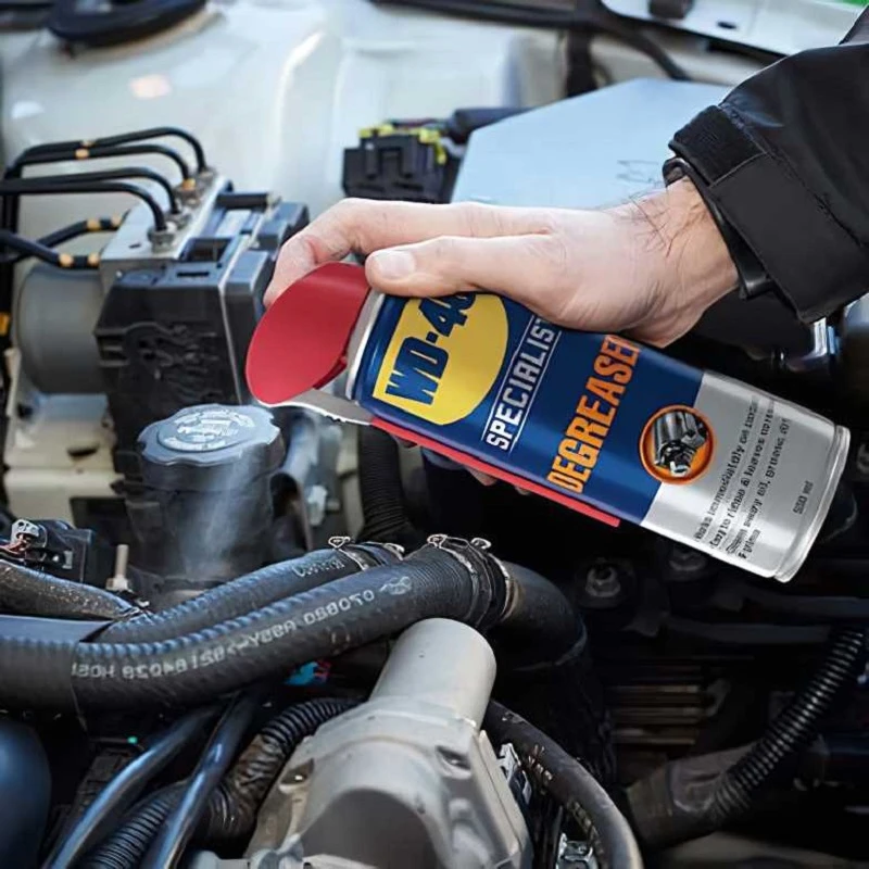 Person using WD40 Specialist Industrial Strength Degreaser Spray on a car engine.