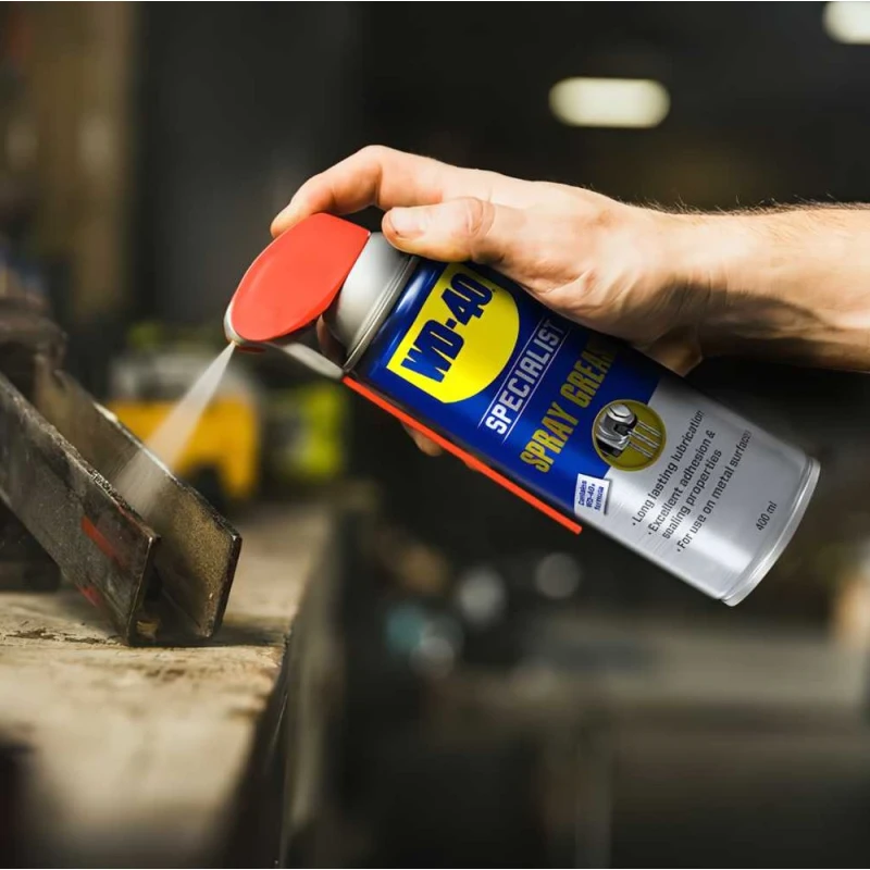 Person using WD40 Specialist Spray Grease Lubricant on metal surface.