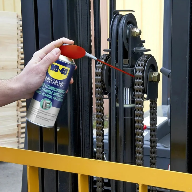 Hand using WD40 Specialist Spray White Lithium Grease Lubricant on machinery chain.
