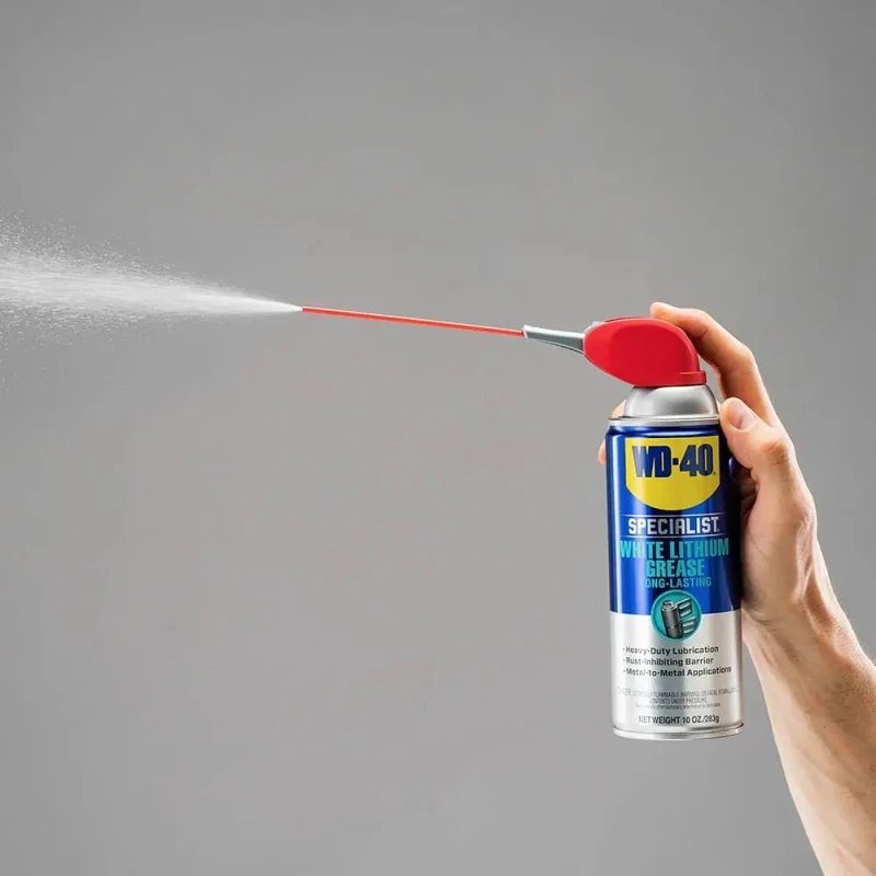 Hand holding a can of WD40 Specialist White Lithium Grease Lubricant with spray nozzle in use.