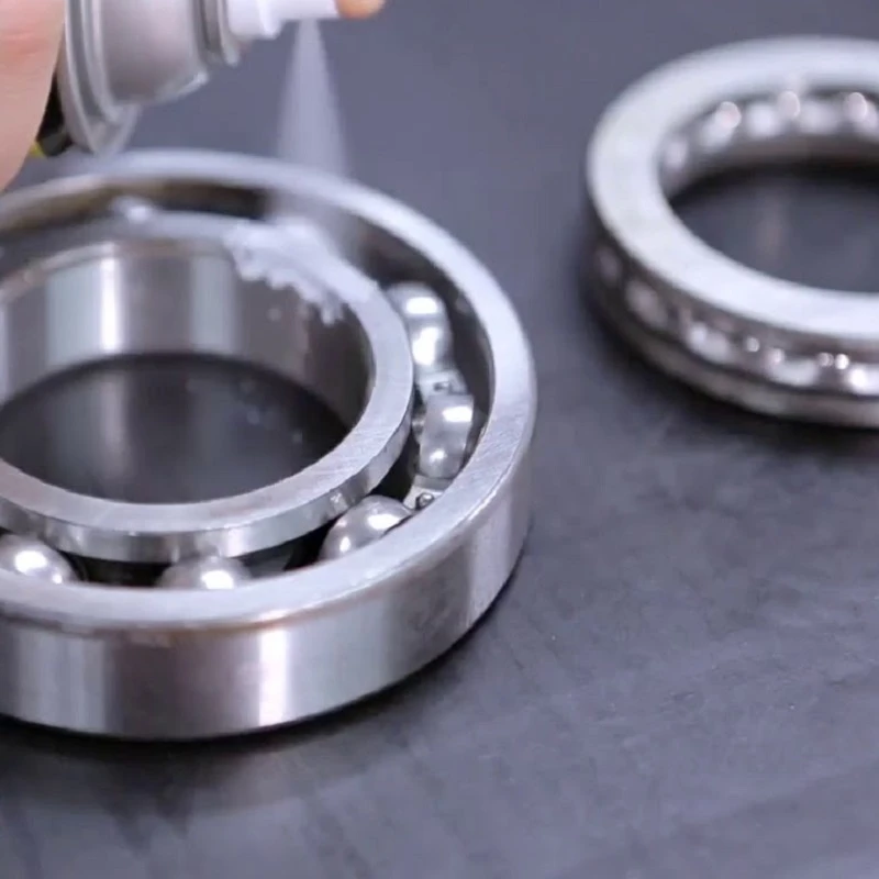 Spraying white lithium grease on metal bearings.