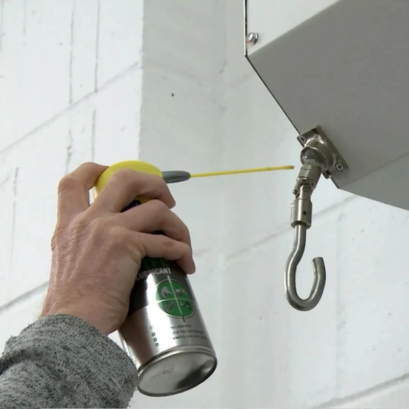 Person using WD40 Specialist Spray Grease Lubricant on a metal hook.