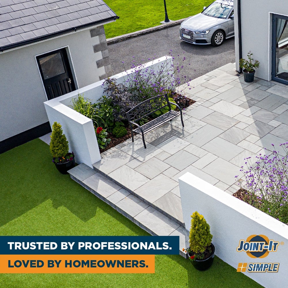 Aerial view of a modern garden patio with light grey paving, clean joints, raised flowerbeds, and a metal bench