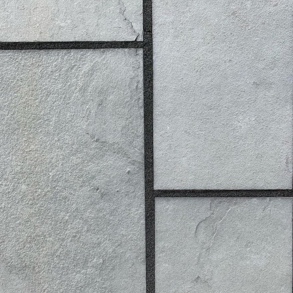 Close-up of grey paving slabs with dark jointing compound, showing a clean rectangular layout and smooth stone texture