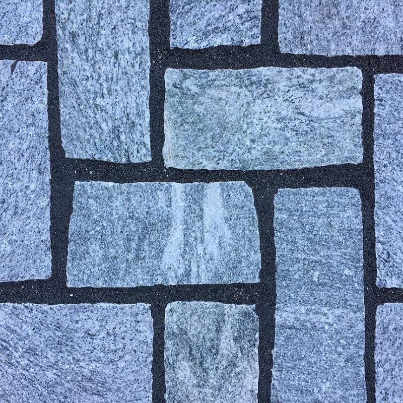 Close-up of grey stone paving with clean dark grey joints, showing neat rectangular slab pattern using jointing compound
