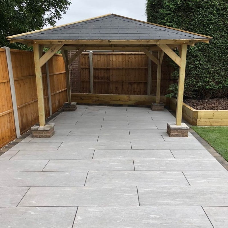Wooden gazebo over paved patio with surrounding fencing