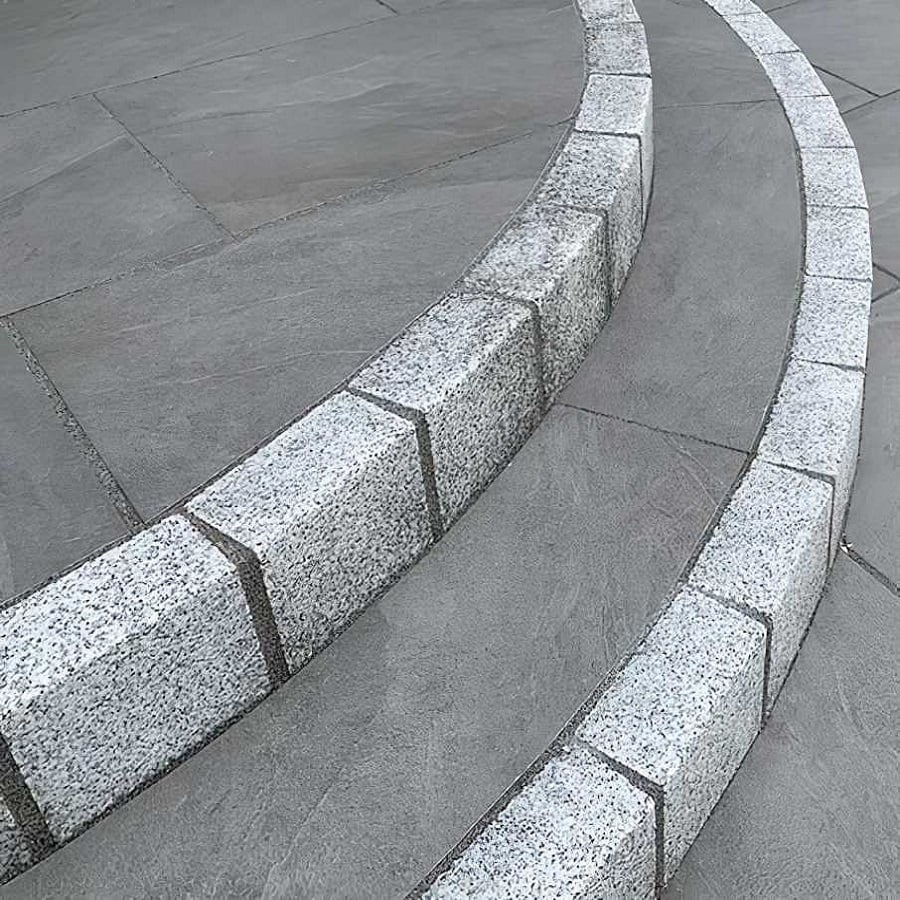 Curved granite steps with adjacent grey paving slabs
