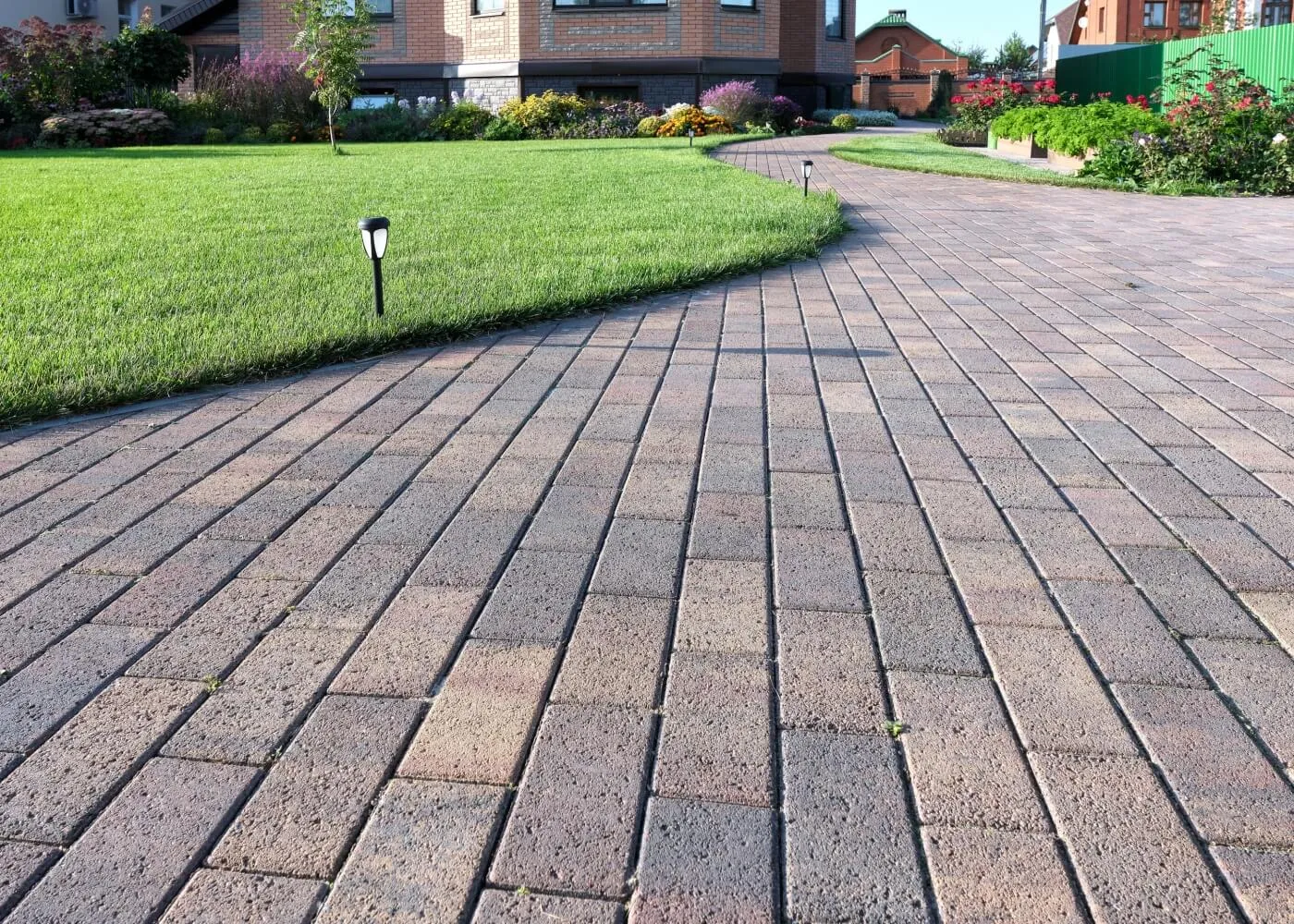 House entrance with paved walkway and garden Brick pathway leading to a house with a well-maintained garden