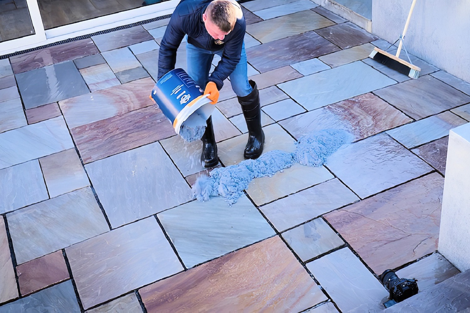 Resin jointing mix being tipped onto stone slabs as part of outdoor paving installation