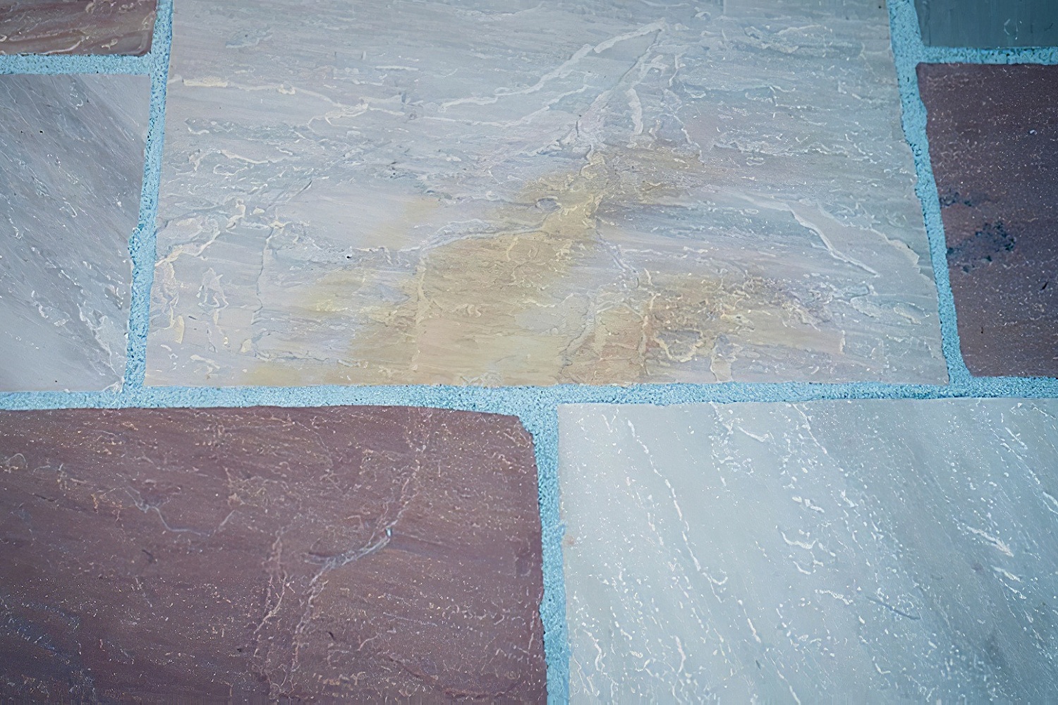 Close-up of multicoloured stone paving slabs with neat dark joints applied using resin jointing compound