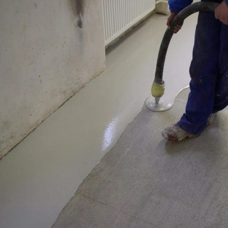 Self-levelling compound being pumped onto a concrete floor as part of subfloor preparation
