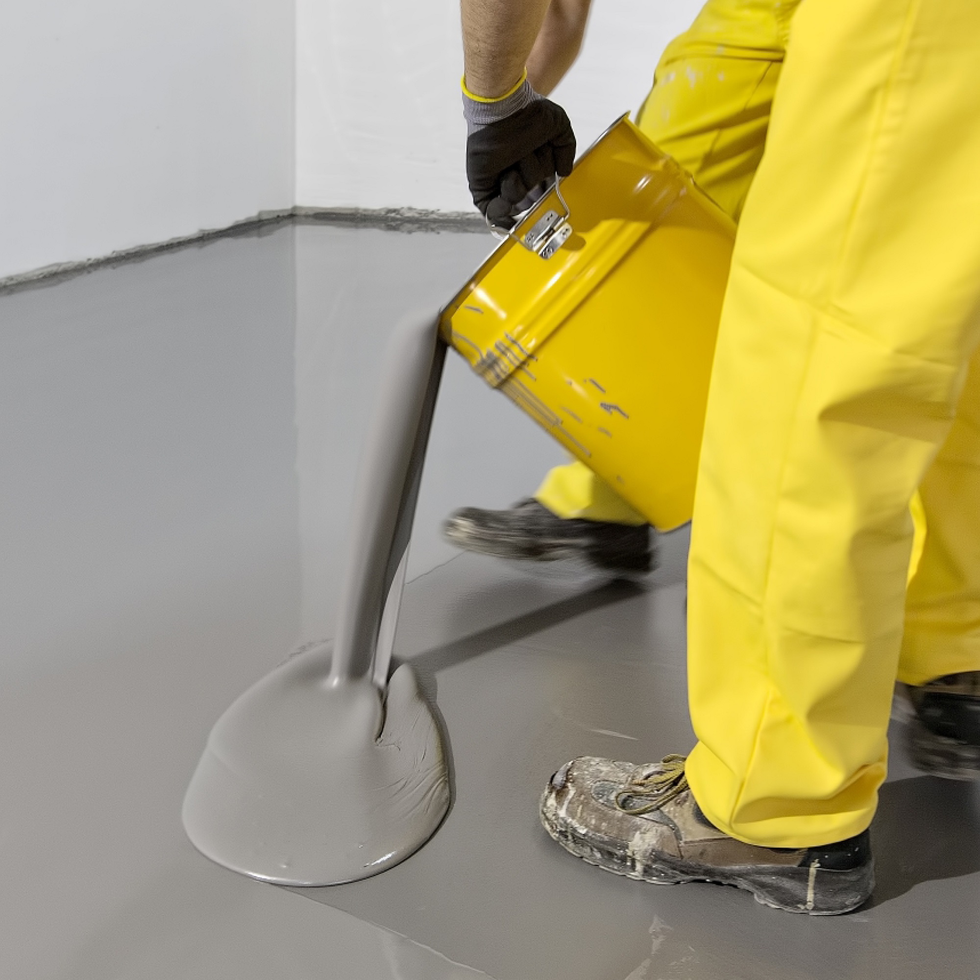 Worker pouring Sika Sikafloor 440 Level self-levelling compound over an underfloor heating system