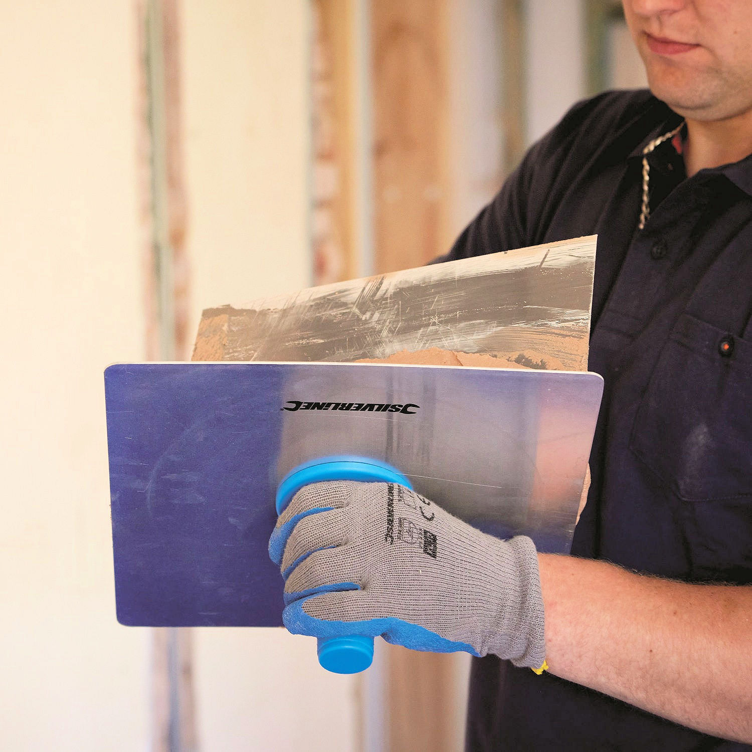 Pair of blue and grey builders gloves with abrasion resistant palms plasterer using a plaster hawk and trowel