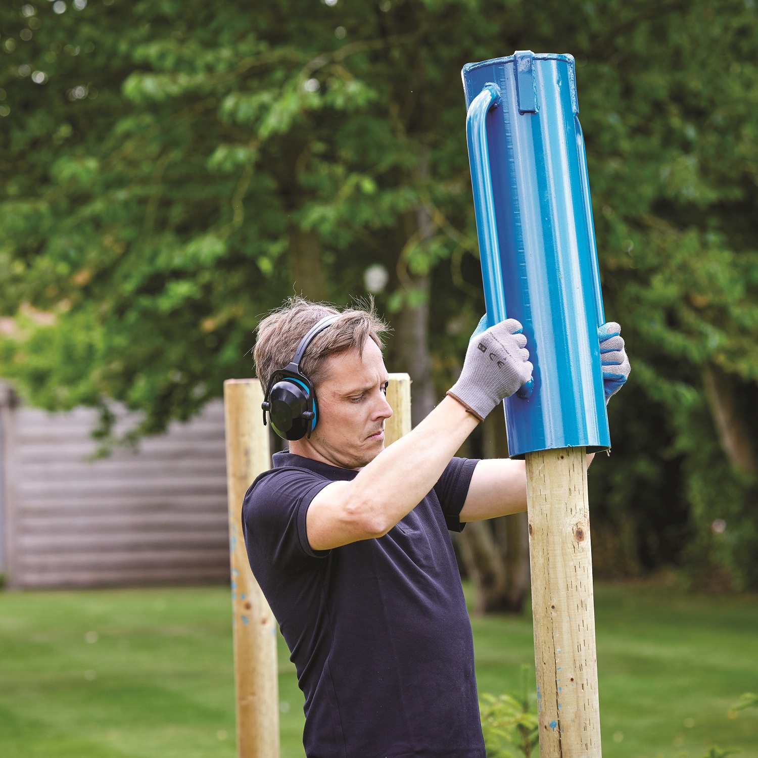 Blue steel rammer tube driver with handles next to a wooden fence post Demonstration