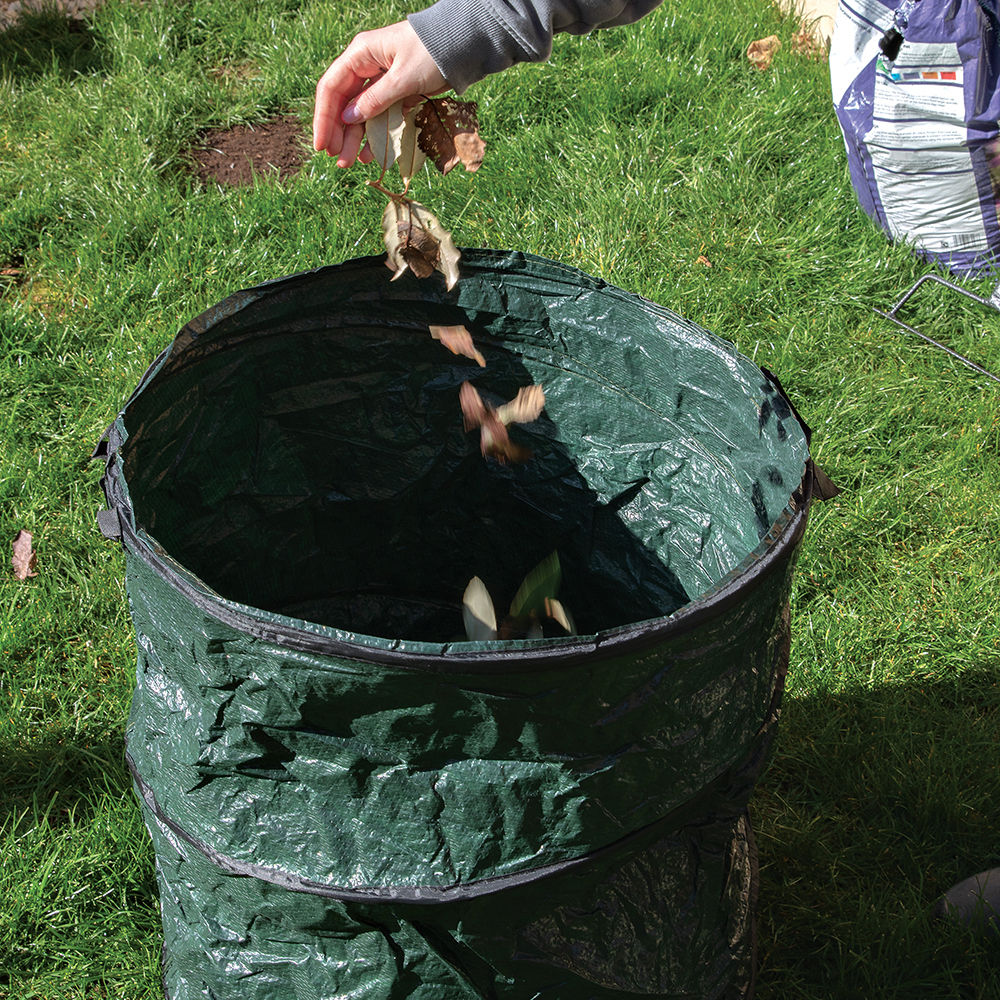 Green pop-up garden refuse sack with handles, open and ready for waste collection leaves being put into pop up bag