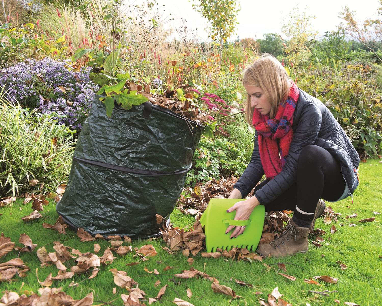 Green pop-up garden refuse sack with handles, open and ready for waste collection leaves being collected and put into pop up bag