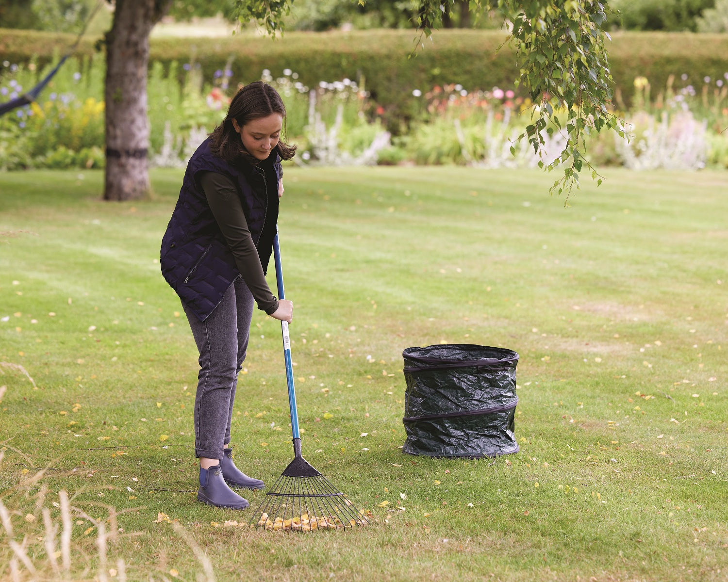 Green pop-up garden refuse sack with handles, open and ready for waste collection raking leaves ready to be but into bag