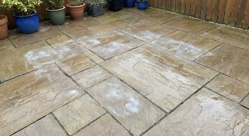 White haze and efflorescence patches on sealed sandstone patio caused by trapped moisture