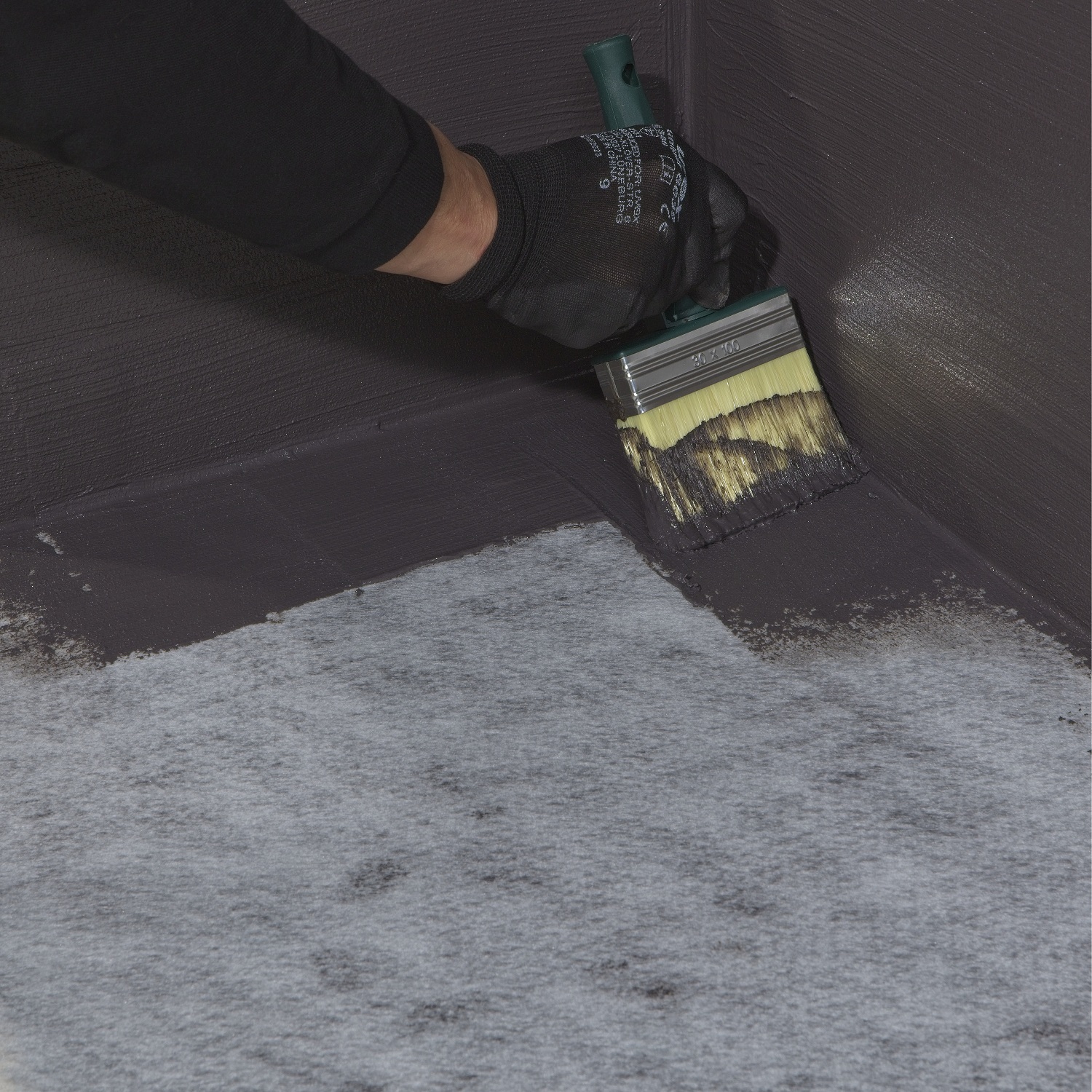 Sika Black Jack 905 black bitumen roof coating being applied with a brush to a roof corner