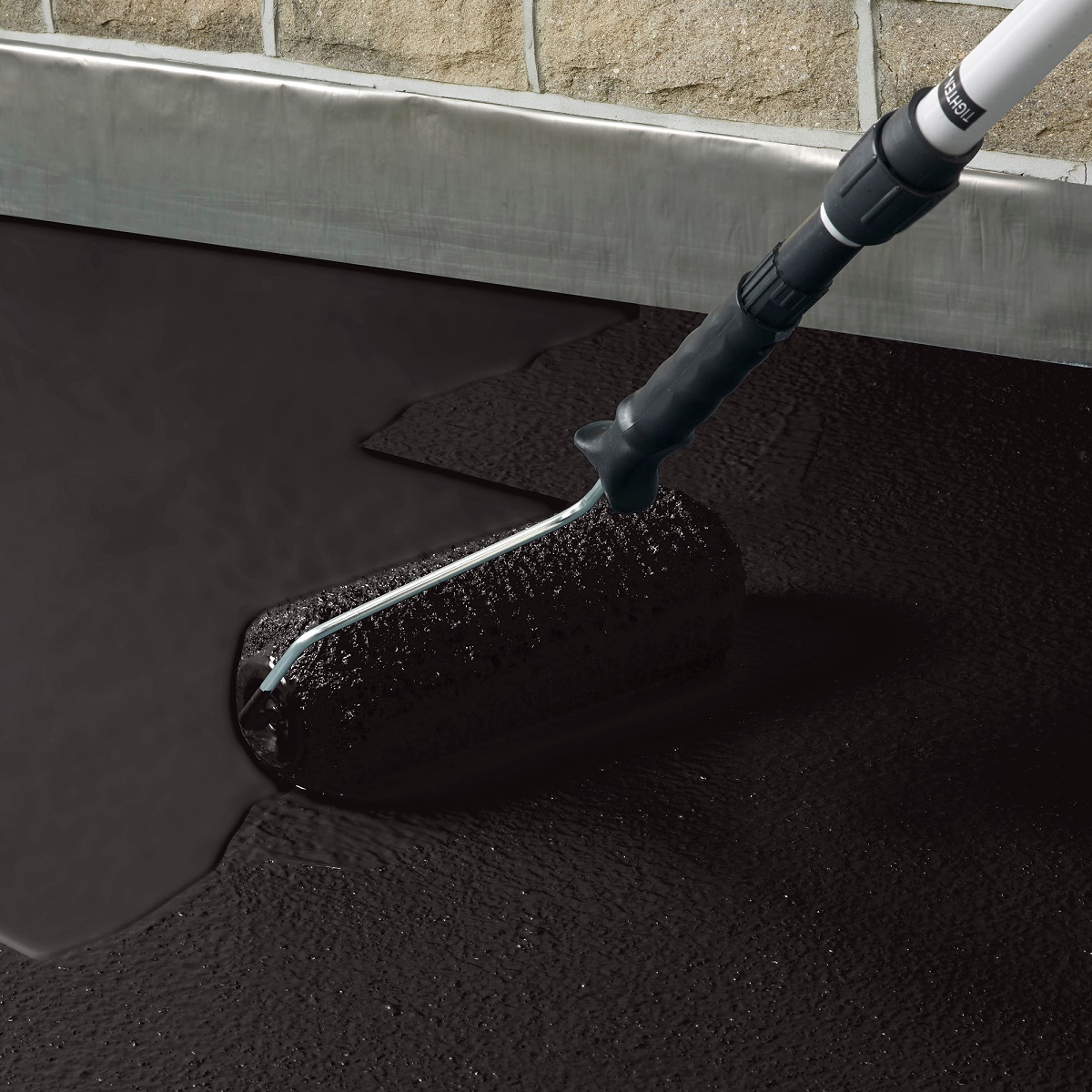 Sika Black Jack 905 black bitumen roof coating being applied with a roller near a wall edge