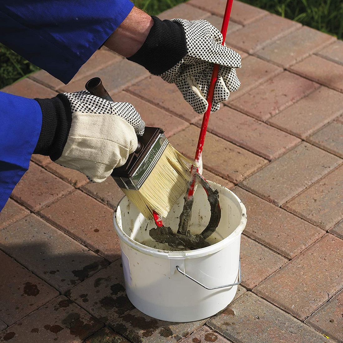 Cleaning cement residue from mixing paddle and tools in bucket using brush and solution