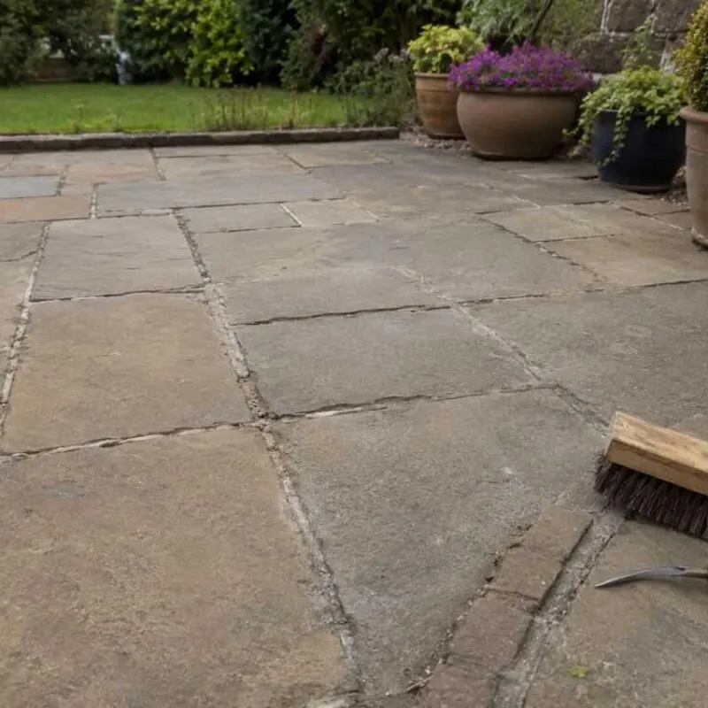 Failed paving joints showing worn jointing compound, open gaps and tools ready for patio joint repair