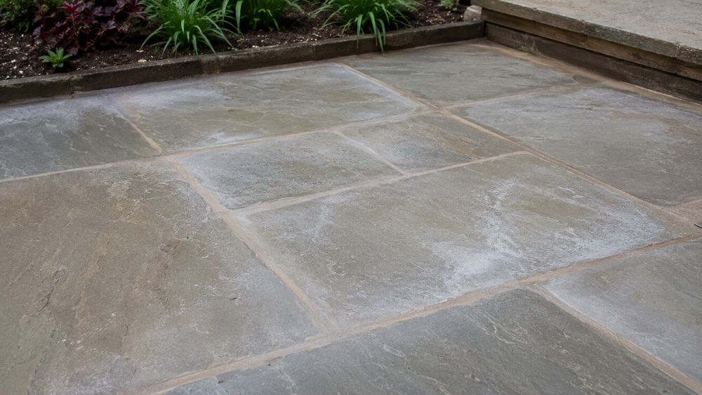 Paving slabs showing light haze and residue around jointing compound after patio jointing