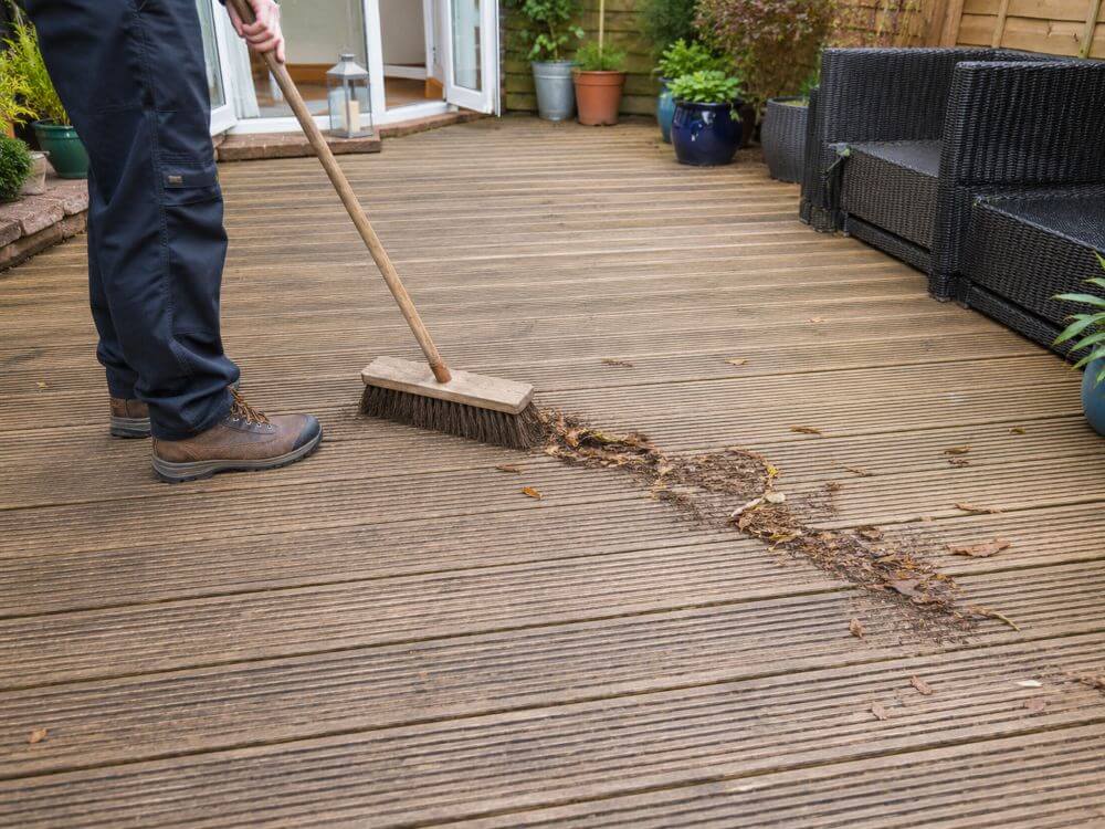 Sweeping loose debris from timber decking before cleaning