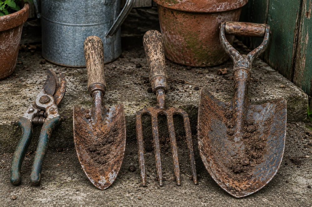 Rusty garden tools with soil on a clean stone surface