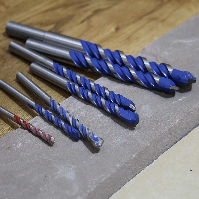 Faithfull multi-material drill bits laid out across timber and a grey block.
