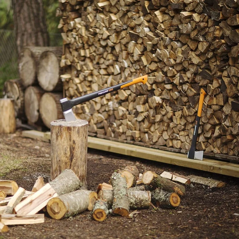 Fiskars splitting axe embedded in a chopping block in front of stacked firewood.