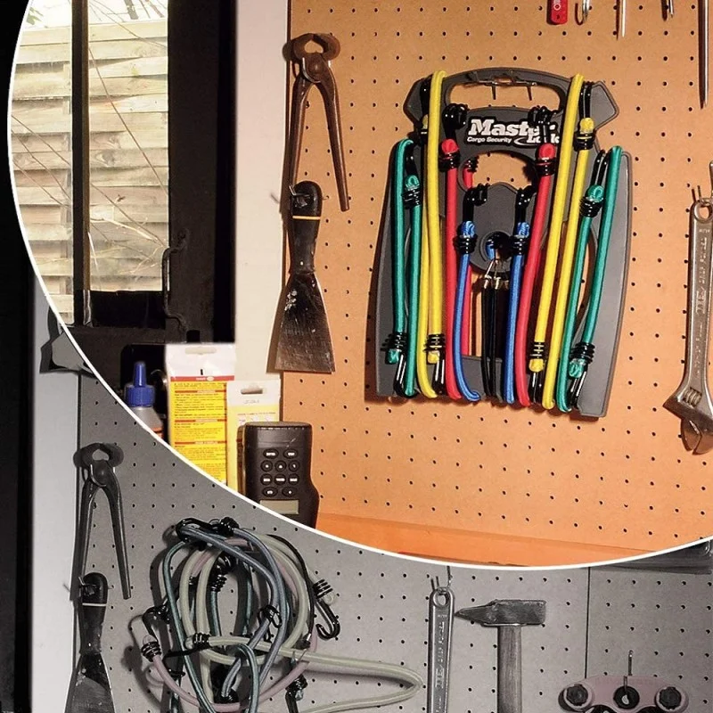 Master Lock bungee cords stored together in their carrier on a workshop pegboard.