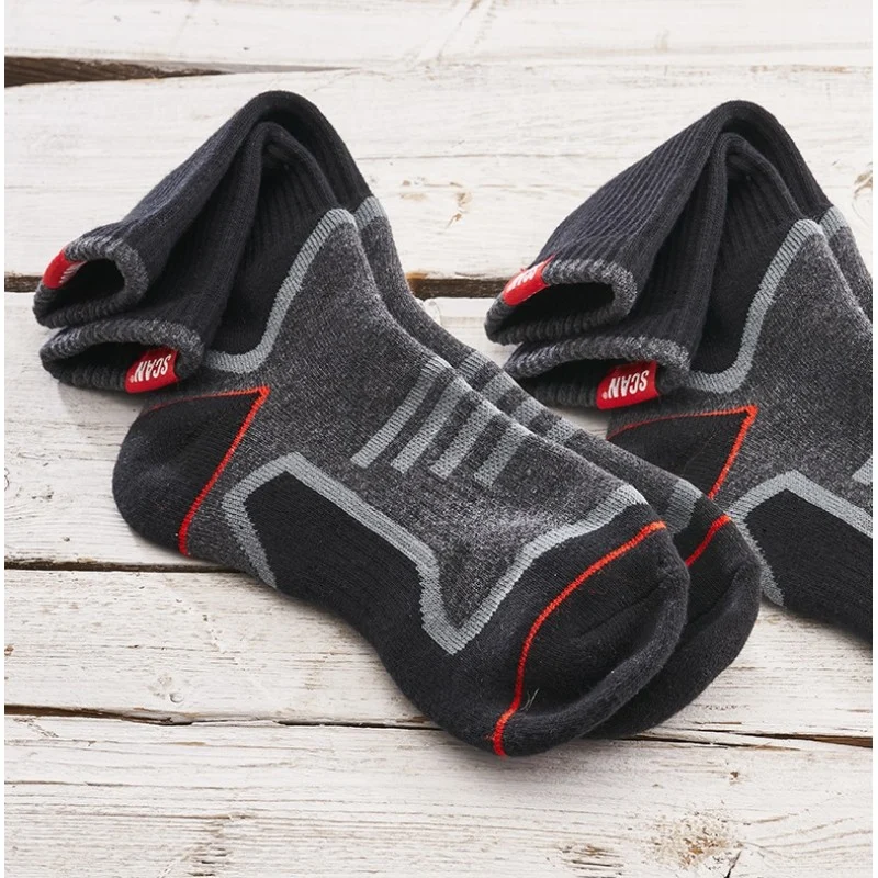 Two folded pairs of Scan work socks resting on a pale wooden surface.