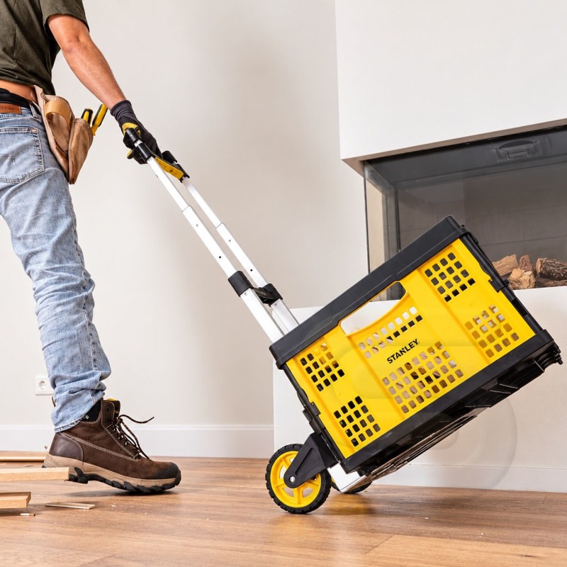 Worker moving a yellow Stanley FT509 basket trolley across an indoor floor